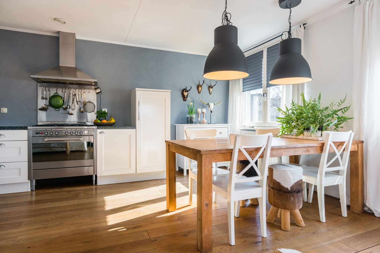 Landelijke woonkeuken met houten tafel en zwarte hanglampen